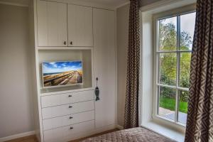 a bedroom with a dresser with a tv on it next to a window at Strand und Meer in List