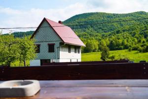 a house with a red roof on top of a fence at Planinarski dom ''Bijele stijene'' Mountain lodge in Tuk Vojni