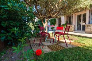 a group of red chairs and a table in a yard at La Villa Capuccine in Nîmes