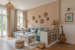 a living room with a blue couch and a guitar at Agapella Apartamenty- Sopot Cottage Ogród 400m od plaży 6 dorosłych i dzieci in Sopot