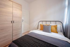 - une chambre avec un lit doté d'oreillers orange et gris dans l'établissement Apartamenty Pamiątkowa 11, 2 rooms, self check in 24h, à Poznań