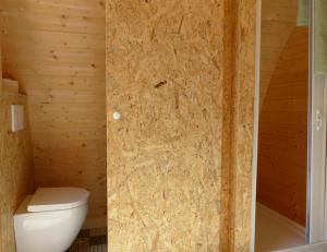 a bathroom with a toilet and a wooden wall at B2B Campingpods Volkach in Volkach