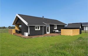 uma casa negra com um deque num campo em Awesome Home In Hirtshals With Kitchen em Hirtshals