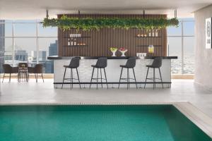 a kitchen with a bar with chairs and a pool at Element by Westin West Bay Doha in Doha