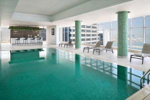 a large swimming pool with chairs and tables in a building at Element by Westin West Bay Doha in Doha