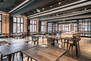 a restaurant with wooden tables and chairs and windows at Ronces Hostel in Pamplona