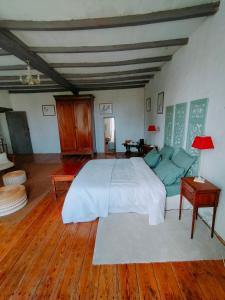 een slaapkamer met een groot wit bed en houten vloeren bij Les Grands Vents in Chervettes