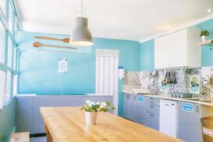 a kitchen with blue walls and a wooden table at Urban Garden Hostel in Lisbon