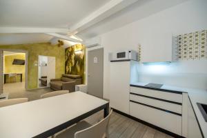 CityU - Grazioli 27 Trento Centro con parcheggio privato في ترينتو: مطبخ وغرفة معيشة مع كونتر أبيض