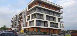 Un edificio alto con coches aparcados delante. en ApartLoft 64 Apartament Zator, en Zator