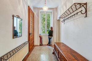 Eine Frau, die im Flur steht und aus dem Fenster schaut. in der Unterkunft Villa by @ Home Hotel Locarno in Locarno