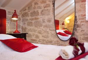 a bedroom with a bed with red pillows and a mirror at Bed & Breakfast Vila Baguc in Split