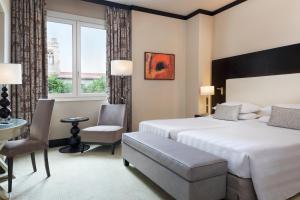 a hotel room with two beds and a table and chairs at Sina Villa Medici, Autograph Collection in Florence