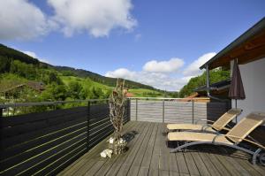 a deck with two chairs and a plant on it at ZeiTraum Ferienwohnung Rohrhardsberg in Elzach