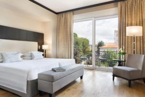 a bedroom with a bed and a chair and a large window at Sina Villa Medici, Autograph Collection in Florence