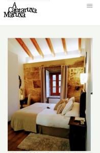 a bedroom with a bed and a table and a window at A Cantaruxa Maruxa Turismo Rural in Mondariz