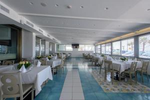 a restaurant with white tables and chairs and windows at Hotel Ancora in Pontecagnano