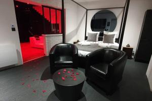 a bedroom with a bed and a black chair and a chair at Bayeuzen - Le Baldaquin - Nuitée avec Spa Privatif in Bayeux
