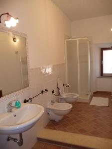 een badkamer met 2 wastafels, een toilet en een spiegel bij La Mandola in Castiglione dʼOrcia