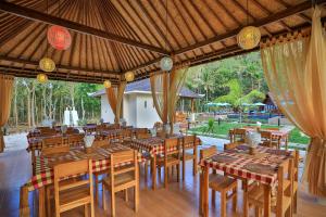 um restaurante com mesas e cadeiras de madeira e um pátio em Mahaloka Valley Nusa Penida em Nusa Penida