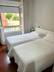 2 camas en una habitación con ventana en APARTAMENTO LA PICOTA, en Liencres