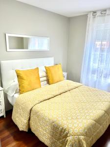 Un dormitorio con una cama con almohadas amarillas y una ventana en APARTAMENTO LA PICOTA, en Liencres