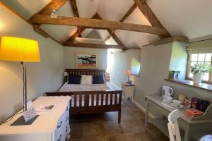 a bedroom with a bed and a desk with a lamp at Little Old Barn at Manor Farmhouse in West Chinnock