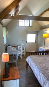 una camera con letto e tavolo con lampada di Little Old Barn at Manor Farmhouse a West Chinnock
