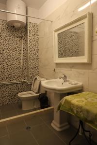 La salle de bains est pourvue d'un lavabo, de toilettes et d'un miroir. dans l'établissement Margarita Guest House, à Berat
