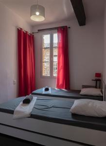 1 dormitorio con 2 camas y cortinas rojas en Le Castelviel, en Albi