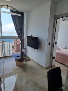 a living room with a bed and a television on a wall at Cielo de Benidorm in Benidorm