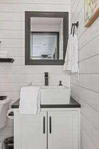a white bathroom with a sink and a mirror at New Wilderness Hideout-Cozy Container Home in Fredericksburg