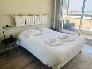 ein Schlafzimmer mit einem großen weißen Bett mit Handtüchern darauf in der Unterkunft Sur le sable 2 3 pers WIFI in Boulogne-sur-Mer