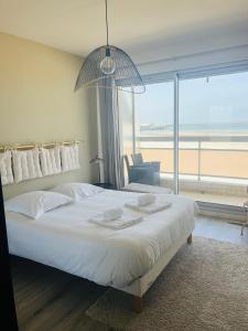 Schlafzimmer mit einem großen weißen Bett und einem großen Fenster in der Unterkunft Sur le sable 2 3 pers WIFI in Boulogne-sur-Mer