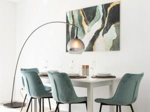 a dining room with a white table and green chairs at MICOA: Tiefgarage/Netflix/Highspeed Arbeitsplatz in Gelsenkirchen