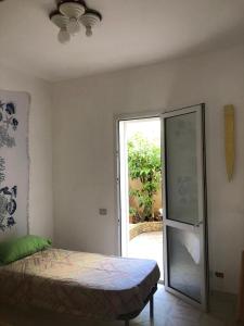 een slaapkamer met een bed en een glazen schuifdeur bij Casa Icaro in Marinella di Selinunte