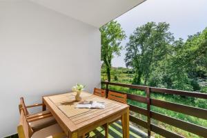 una mesa de madera en un balcón con vistas a los árboles en Apartments Villa Verde, en Novigrad Istria