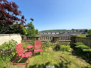 three red chairs and a table in a yard at Stylish Central Apartment with Parking - Garden and Workspace in Bath