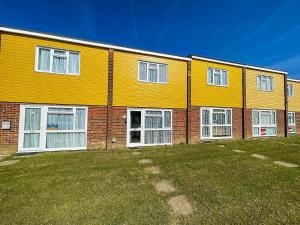 a large orange building with white windows and a yard at Lovely 5 Berth Chalet In The Coastal Village Of Hemsby Ref 18164b in Hemsby