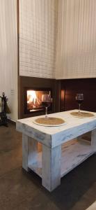 una mesa con 2 copas de vino y una chimenea en La Casita del Arroyo, en Arroyo Frío