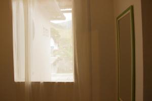 a window with a white curtain in a room at Pousada no Sana Donna Leda in Sana