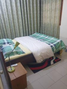 uma pequena cama num quarto com um candeeiro sobre uma mesa em Appart. For you N° 1. Douala Logpom sur le goudron em Douala