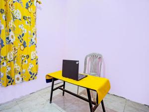 a yellow table with a laptop on top of it at SPOT ON 92564 Kemangi Asri Kost in Banyuwangi