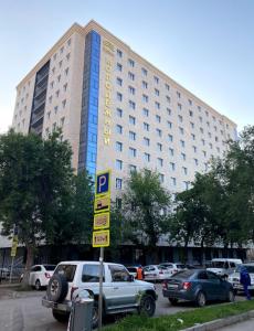 ein großes Gebäude mit davor geparkt in der Unterkunft Апартаменты в центре, в новом доме in Almaty