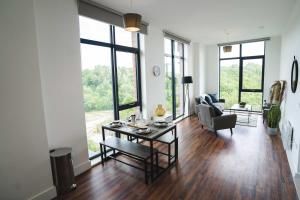 een woonkamer met een tafel, stoelen en ramen bij Modern 2-Beds - City Centre - FREE Wi-Fi - New - in Sheffield