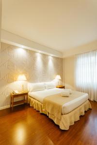 ein Schlafzimmer mit einem großen weißen Bett mit zwei Lampen in der Unterkunft Dorá Hotel Buenos Aires in Buenos Aires