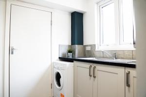 a white kitchen with a sink and a washing machine at Charming Retreat in the heart of the City in Liverpool