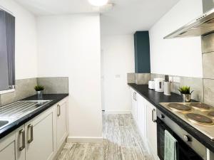 a kitchen with white cabinets and black counter tops at Charming Retreat in the heart of the City in Liverpool