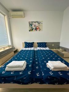 a bedroom with a blue bed with towels on it at Sunshine Romance Apartment in Kranevo