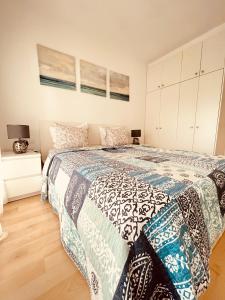 Schlafzimmer mit einem Bett mit einer blauen und weißen Bettdecke in der Unterkunft Sunny apartment Sa Boadella big solarium sea view in Lloret de Mar
